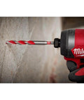 Milwaukee electric hammer drill with red body; close-up of carbide drill bit drilling into concrete wall.