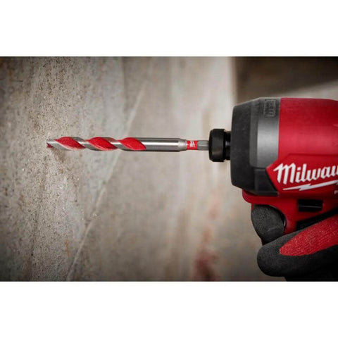 Milwaukee electric hammer drill with red body; close-up of carbide drill bit drilling into concrete wall.
