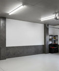 Modern garage interior with concrete stamped walls, white ceiling, and fluorescent lighting featuring storage shelves in the corner.