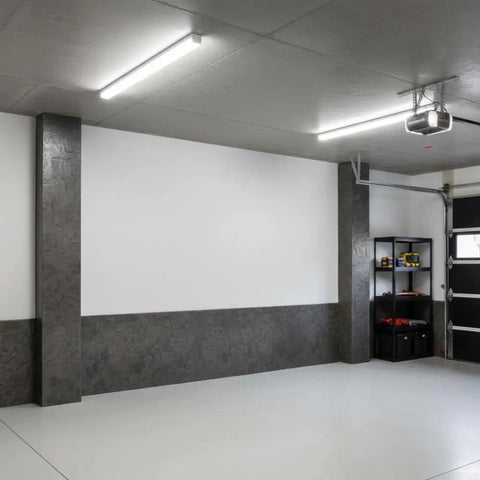 Modern garage interior with concrete stamped walls, white ceiling, and fluorescent lighting featuring storage shelves in the corner.
