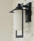 Top Tier Modern Outdoor Wall Sconce Featuring Waterproof Black Matte Aluminum Bracket And Cylindrical Glass Shade mounted on a wall.