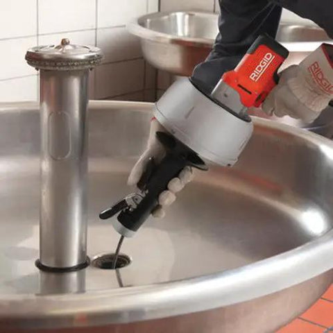 K-45AF Air Powered Drain Cleaner 230V Drum Auger being used on a stainless steel sink drain for sewer pipe clogs.