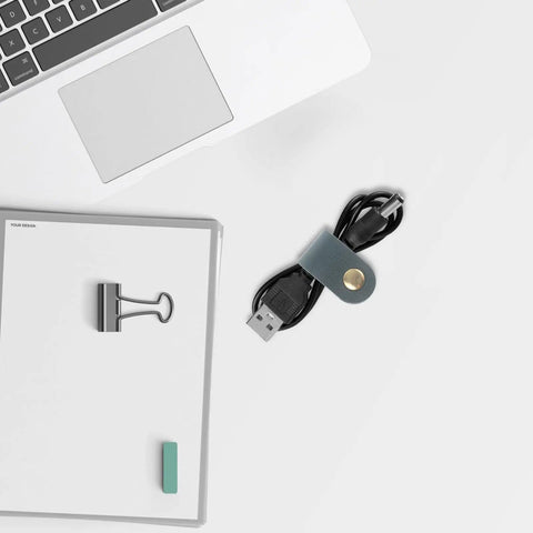 Five Piece Leather Cord Wraps Keep Your Computer Rig Hella Neat With Durable Sock Style Cable Organizers For Usb Chargers Phone Wires And Audio Equipment on a desk next to a USB cable.