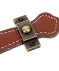 Close-up of vintage leather trunk handle replacement for cabinets and drawers, brown leather pull with brass hardware.