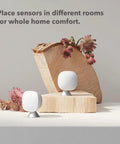 SmartSensor 2-Pack for Temperature and Occupancy Detection, Keeps Rooms Cozy by Relaying True Room Temp to Your Thermostat Up to 60 Feet Through Walls, Hands-Free Auto-Adjusts Temperature, Real-Time Occupancy Awareness, Simple Smart Home Upgrade. Two white room sensors on wood blocks.