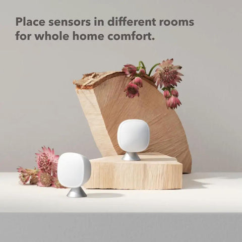 SmartSensor 2-Pack for Temperature and Occupancy Detection, Keeps Rooms Cozy by Relaying True Room Temp to Your Thermostat Up to 60 Feet Through Walls, Hands-Free Auto-Adjusts Temperature, Real-Time Occupancy Awareness, Simple Smart Home Upgrade. Two white room sensors on wood blocks.