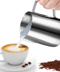 Hand pouring milk from Stainless Steel Milk Frothing Pitcher For Latte Art 12 Ounce Barista Grade Pouring Jug into coffee cup