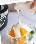 No Sweat Automatic Yogurt Maker With Four Leakproof Glass Jars pouring homemade yogurt over fruit salad.