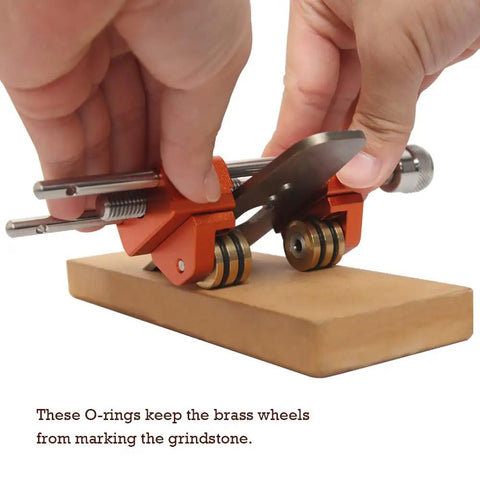 Hands adjusting honing guide sharpening jig for chisels and planes with reversible wheel mounting on a grindstone.