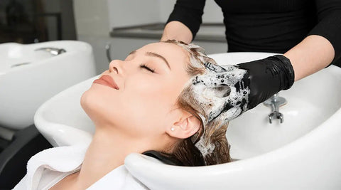 Woman receiving hair wash at salon sink with Pro Grade Shampoo Bowl Faucet Kit with Vacuum Breaker, Hose and Sprayer in use