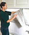 Woman installing NASA Tech White Reflective Foam Core Garage Door Insulation Kit With Upgraded Tape Includes 4 Rolls Of 9ft By 2ft Foil Back Insulation Duty Double Sided Tape Razor Squeegee Easy Install Sound Deadening Lightweight Class A Fire Rated Made In USA