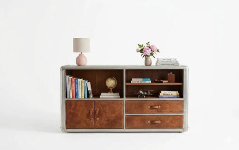 Knockout Aviator Sideboard Cabinet Drops That Aero Industrial Heat With Wraparound Weathered Brown Leather Riveted Silver Trim And Massive Storage Building A Solid 54 Inch Credenza Console Table For Any Cool Living Space showcasing books, globe, and lamp.