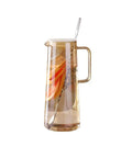 A Game Changer High Borosilicate Glass Pitcher With Secure Tight Lid And Long Mixing Spoon One Point Six Liter, filled with iced tea and fruit.
