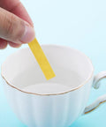 Hand dipping PH Test Strips From One To Fourteen Universal Litmus Indicator Eighty Strips for Soap Soil Water Aquarium Use in a teacup