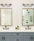 3 Light Vanity Bar Over Mirror With Brushed Nickel Finish And Clear Glass Shades Above Dual Bathroom Mirrors