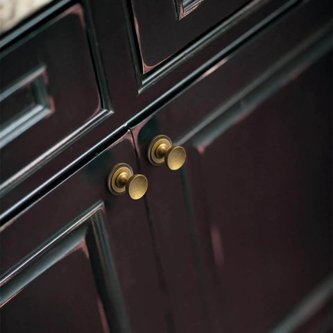 Antique Brass Cabinet Knobs With Gear Like Backplate Six Pack installed on dark cabinet, highlighting vintage round cup design.