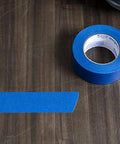 Duck Brand Clean Release painter's tape roll with blue tape strip on wood surface