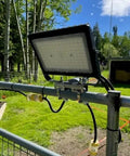Junction Box Pipe Mount Bracket With Adjustable Clamps For Pole Or Wall Installations holding a light fixture outdoors
