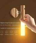 Hand holding wooden LED night light with motion sensor, magnetic base, dual sensing photosensitive and infrared, for bedroom hallway use.