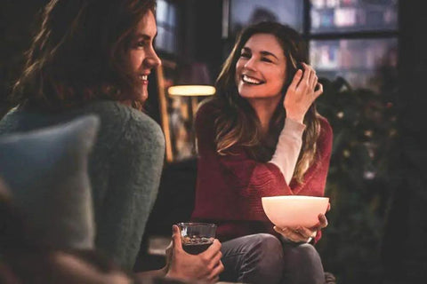 Two people enjoy ambient light from a Go White And Color Portable Dimmable LED Smart Light Table Lamp That Plays Nice With Alexa.