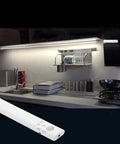 9.8ft Under Cabinet LED Strip Lights With Motion Sensor And Battery Power Auto Or Manual Modes Ideal For Closet Kitchen Bedroom Stairs Basement Trunk And More White 4000K illuminating a modern kitchen countertop with control remote