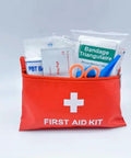 Red compact travel first aid kit pouch with white cross; visible contents include bandages, scissors, prep pad.