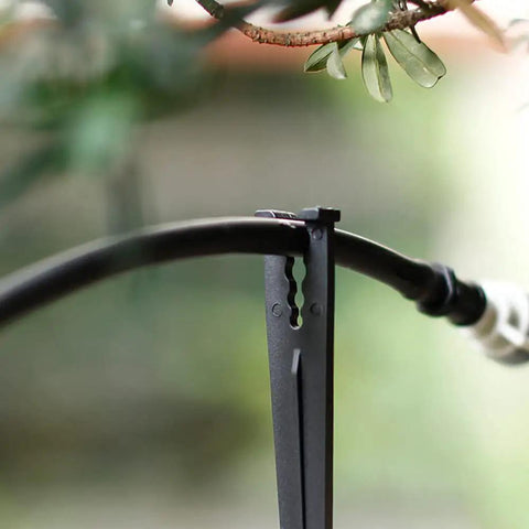 Product image showing a black plastic irrigation stake lifting 1/4 inch drip tubing off the ground. Ideal for garden use.