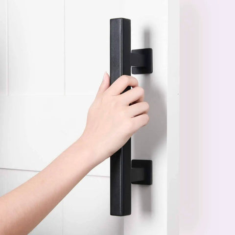 Person gripping two pack 12 inch barn door handles set with rustic two side pull and flush sliding design in black square finish.