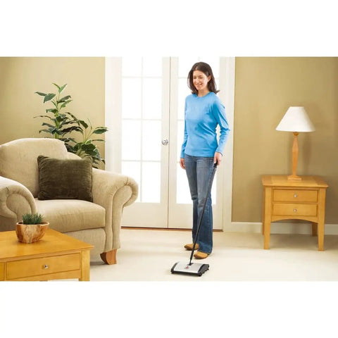 Lightweight Manual Carpet And Hard Floor Sweeper Featuring Dual Rotating Brush Roll Plus Corner Edge Brushes being used on carpet.