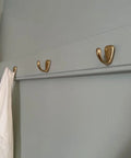 Small Solid Brass Wall Mounted Hanging Hooks Duo Pack Slick Dope Gold Finish on wall holding white clothing.