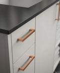 Installed copper notched cabinet pulls on white drawers, showing Copper Asymmetric Notched Cabinet Pull For Cabinets And Furniture.
