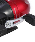 Close-up of red and black closed face spin cast fishing reel with durable plastic and metal components for smooth retrieval.