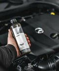 Person holding 500 mL bottle of Perl Coat Plastic And Rubber Protectant For Cars near engine bay
