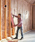 Man installing Top Ticket R-13 Pink Kraft Faced Fiberglass Insulation Roll in a wall cavity for thermal retention.