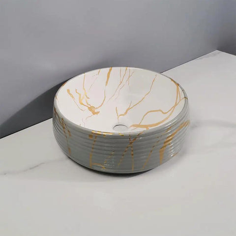 Round ceramic bathroom vessel sink with gold marbling, ideal for home or hotel counter basin use.