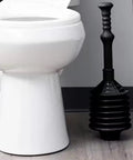 No Sweat Bellows Toilet Plunger Delivers Maximum Thrust For Stubborn Blockages Anti Splash Action For Low Flow Drains Hella Effective Power Plunger With 21 Inch Handle next to a toilet.
