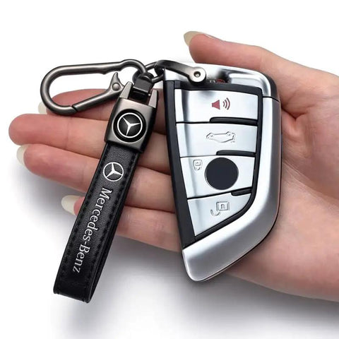 Hand holding Mercedes Benz Tire Valve Caps And Leather Keychain Set featuring a Mercedes-Benz key with premium leather strap
