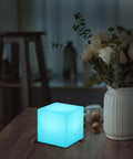 4 Inch Dimmable LED Night Light Mood Cube With 16 RGB Colors, 8 Level Dimming, on a table next to flowers.