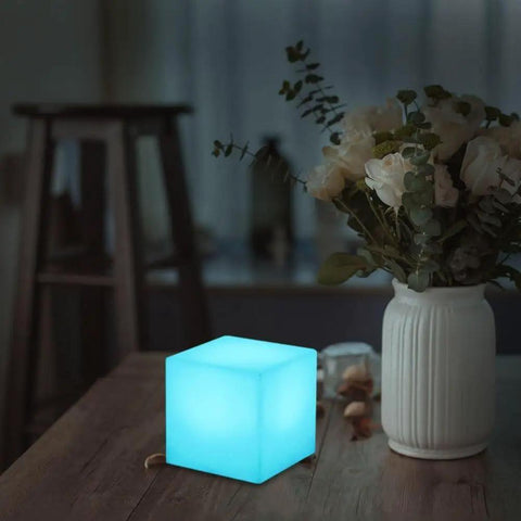 4 Inch Dimmable LED Night Light Mood Cube With 16 RGB Colors, 8 Level Dimming, on a table next to flowers.