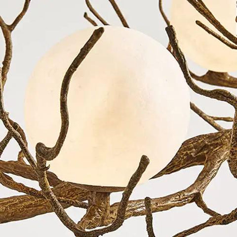 Close-up of a glowing orb fixture from the Sleek Vintage Moon Led Chandelier Boasts Natural Branch Silhouette And Nine Soft Glowing Fixtures.