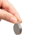 Hand holding silicone pad from Bulk 1000 Pack Silicone No Slip Pads For Drawers And Cabinets beside stacked coins