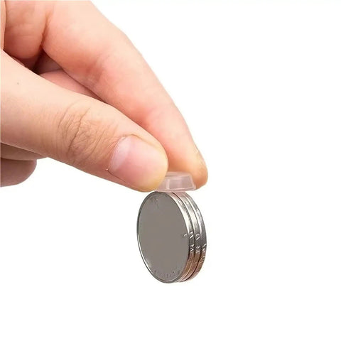 Hand holding silicone pad from Bulk 1000 Pack Silicone No Slip Pads For Drawers And Cabinets beside stacked coins
