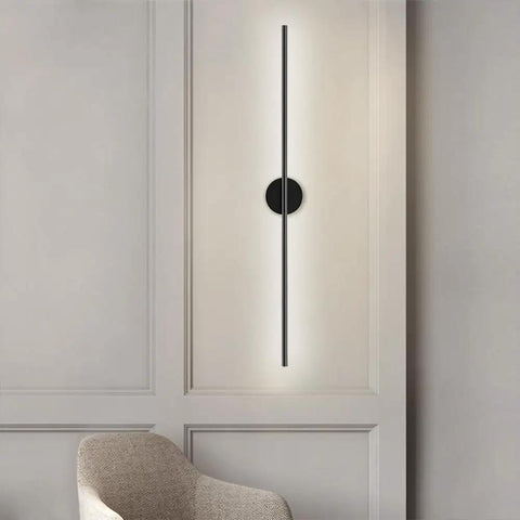 DFEDHF Minimalist Black Linear Wall Sconce - Slim LED Stick Light Fixture for Indoor Use, mounted on a wall beside a modern chair.