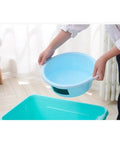 Heavy Duty Black PVC Repair Sealant Tape Waterproofs Leaks And Cracks Instantly For Kitchen Pipes Drains And Bathroom Fixings With Super Sticky Adhesion That Holds Tight Without Dripping Or Peeling Off No Matter How Wet It Gets So You Can Banish Those. Light blue plastic bowl held by a person above a green container in a bright room.