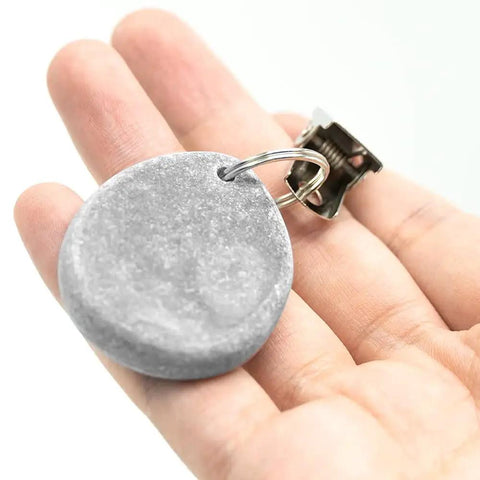 Close-up of No Slip Marble Tablecloth Weights With Clips, showing grey pendant stone and metal clip in hand.