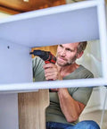 Man using Rock Solid 18V Cordless Drill Driver With Kickass 45 Nm Torque to assemble furniture indoors.