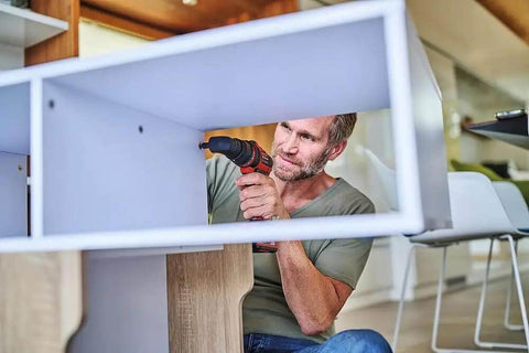 Man using Rock Solid 18V Cordless Drill Driver With Kickass 45 Nm Torque to assemble furniture indoors.