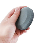 Hand holding Dual Grit Axe Sharpener And Hatchet Stone With 120 Grit On One Side And 280 Grit On The Other For Extra Coarse To Fine Grinding.