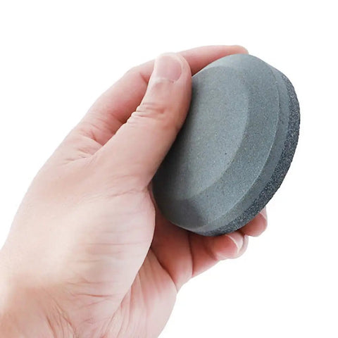 Hand holding Dual Grit Axe Sharpener And Hatchet Stone With 120 Grit On One Side And 280 Grit On The Other For Extra Coarse To Fine Grinding.