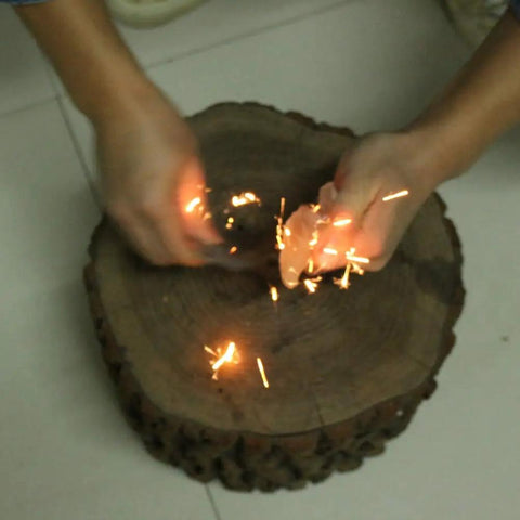 Tough As Nails Fire Starter Tool For Camping And Hiking in use, carbon steel striker creating sparks on a wooden surface.